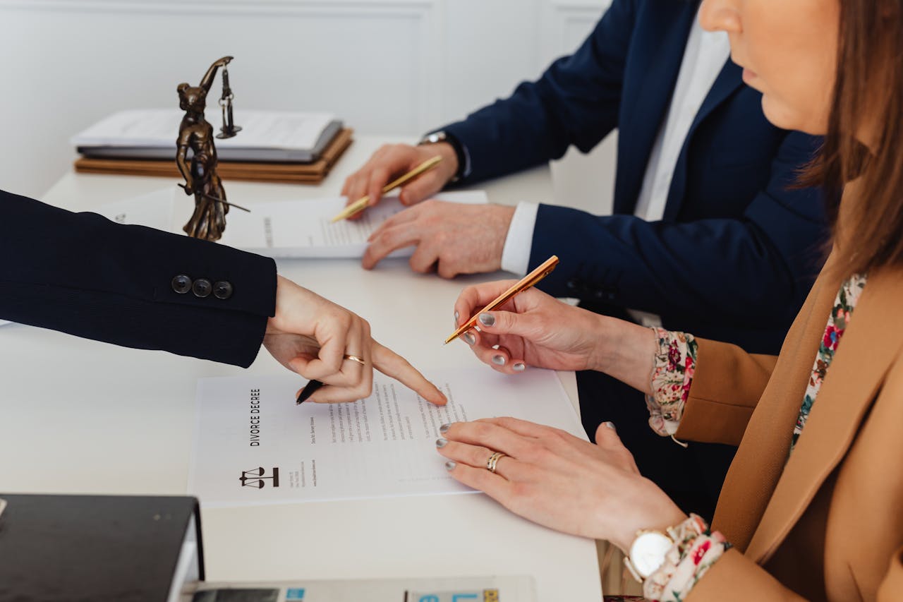 expertise-01 Hands signing a divorce decree, with a justice statue nearby, symbolizing legal proceedings.